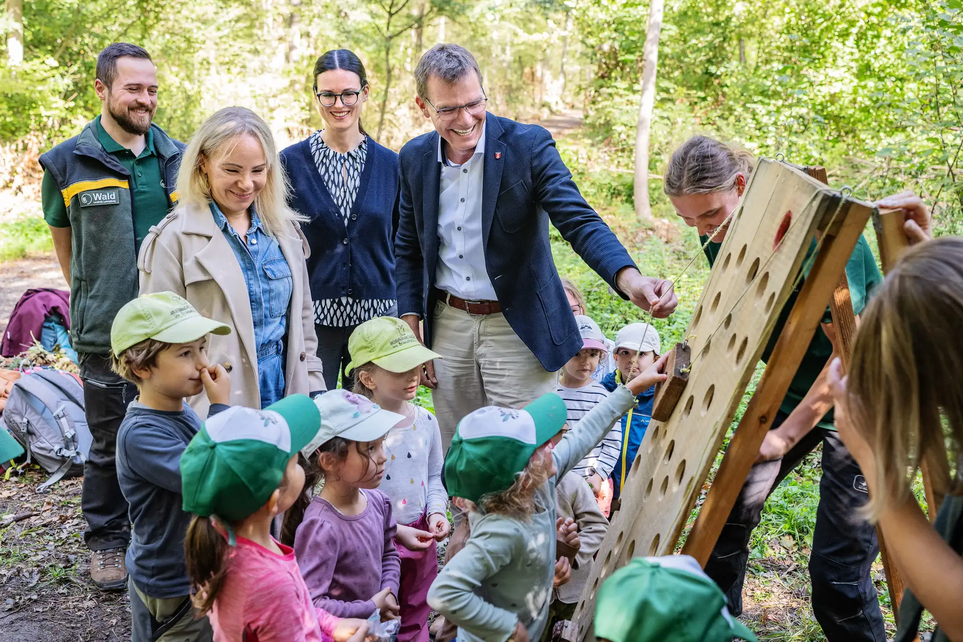 Personengruppe im Wald bei einem Schild am mobilen „Wusel-Walderlebnispfad“