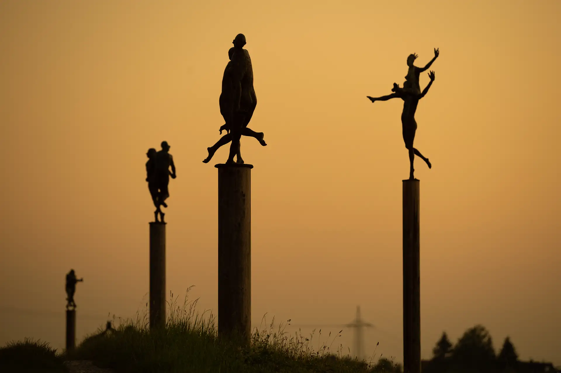 Zwei Personen in einer Allee vor einer Skulpturenlandschaft.