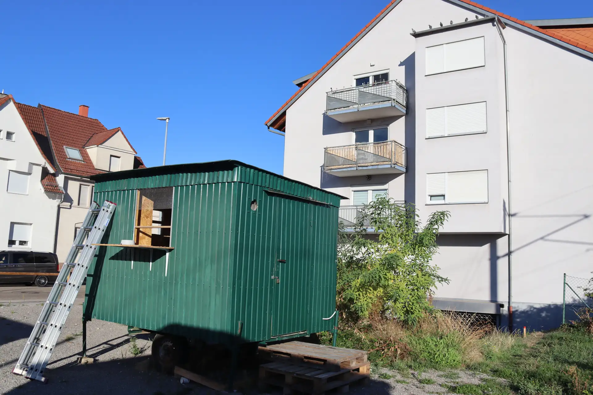 Taubenhaus mit Dachbereich vor mehreren Wohnhäusern.