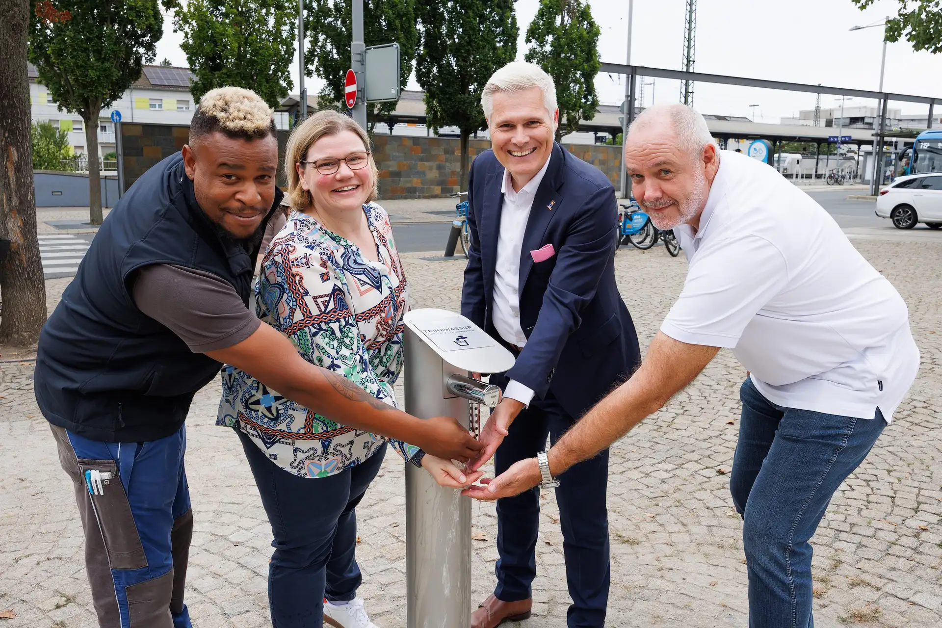 Stadtwerke- Netzmonteur Sergio Ruf, Stadtwerke-Geschäftsführerin Martina Braun, OB Matthias Steffan und Olaf Türke, Leiter des Technischen Teams der Stadtwerke nehmen den neuen Trinkwasserbrunnen vor dem Kaufland in Betrieb.