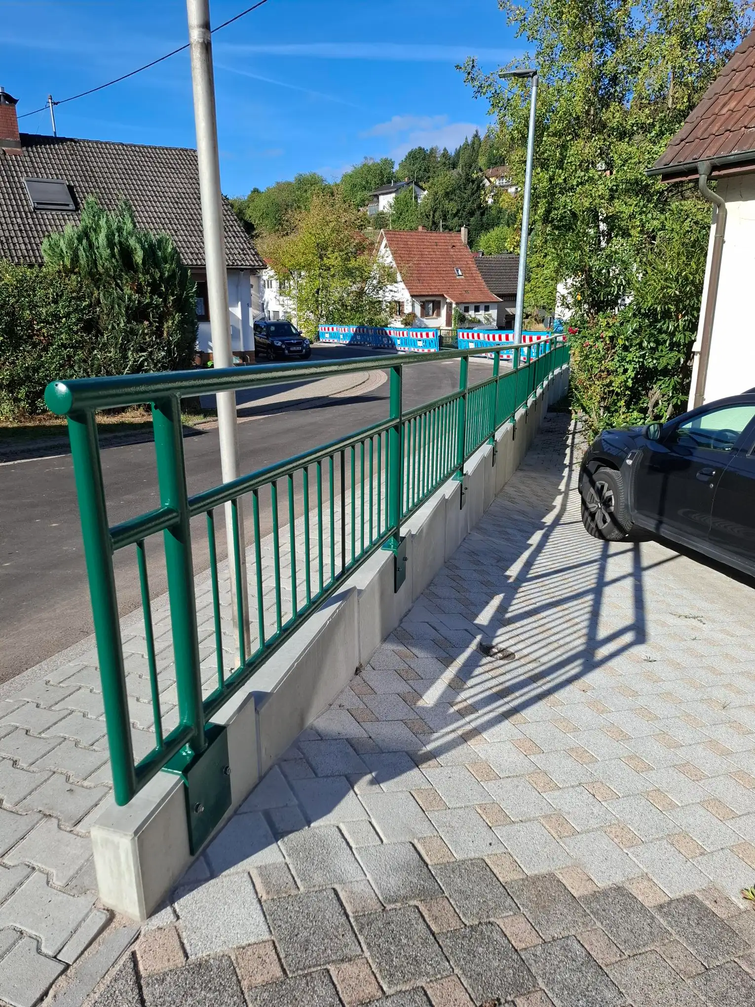 Grünes Stahlrohrgeländer an einer sanierten Stützwand in der Wiesentalstraße in Michelbach