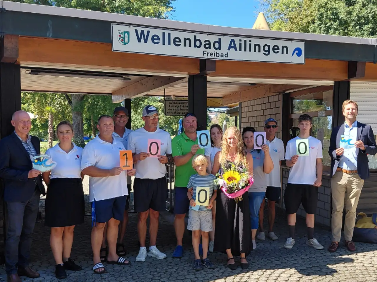 Das Team des Wellenfreibades Ailingen freut sich über die 100.000ste Besucherin: Frau König (Mitte mit Blumen).